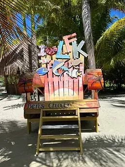 A wooden chair with a sign on top of it on a beach.