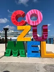 A colorful sign that says `` cozumel '' in front of a cruise ship.