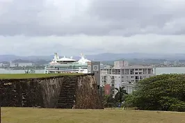 A cruise ship is sitting on top of a cliff overlooking a city.