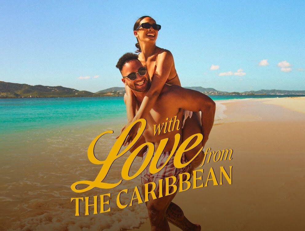 A man is carrying a woman on his shoulders on the beach.