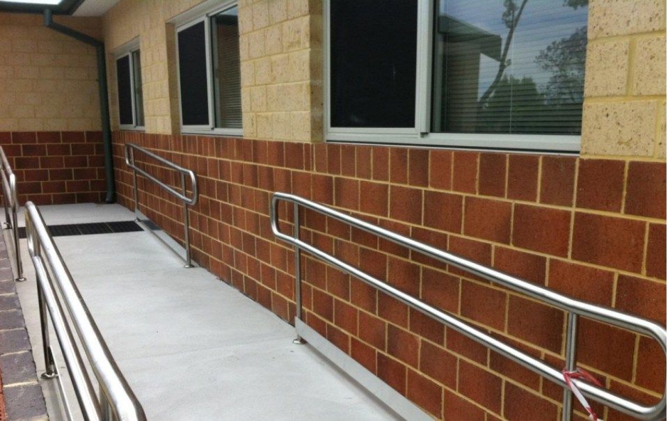 A brick building with a ramp and a stainless steel railing