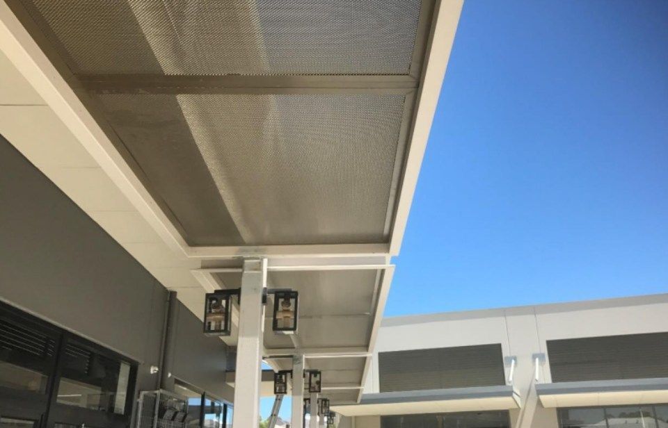 A covered walkway between two buildings with a blue sky in the background.