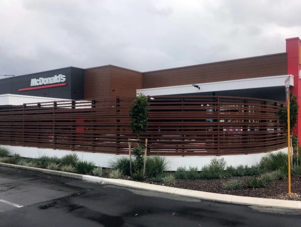A mcdonald 's restaurant with a wooden fence around it.
