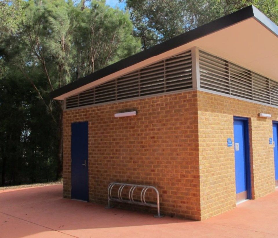 A brick building with blue doors and a bench in front of it