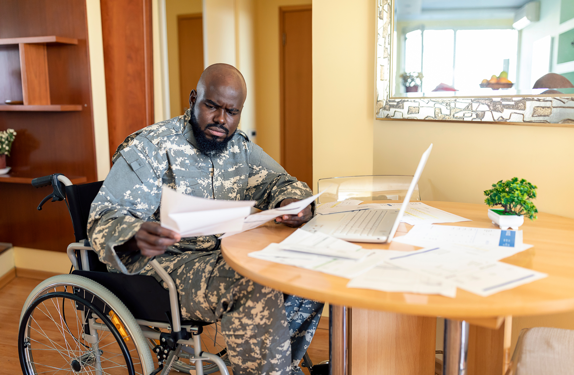 An elderly man in a wheelchair is holding an american flag.