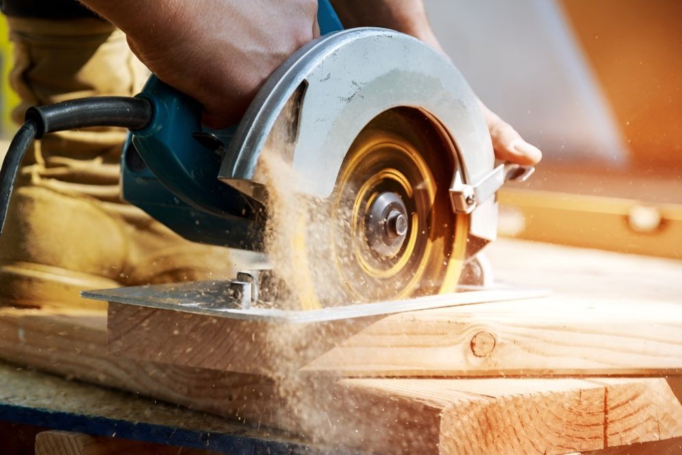 A Person is Using a Circular Saw to Cut a Piece of Wood — Mick's Carpentry & Maintenance In Machans Beach, QLD