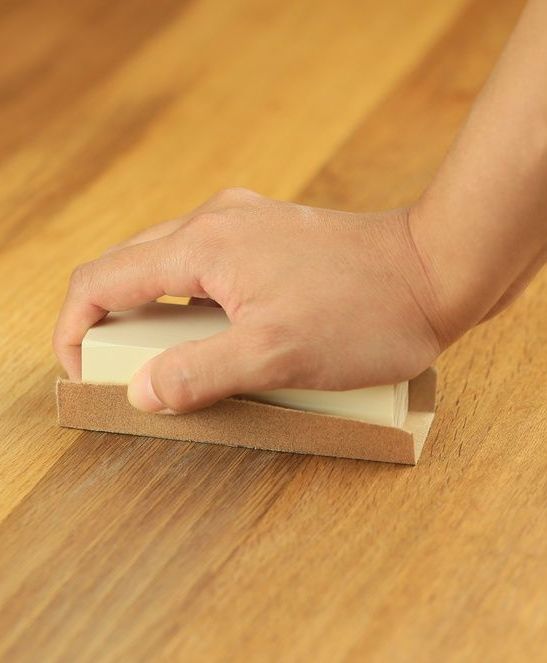 A Person is Using a Sanding Block on a Wooden Floor — Mick's Carpentry & Maintenance In Machans Beach, QLD