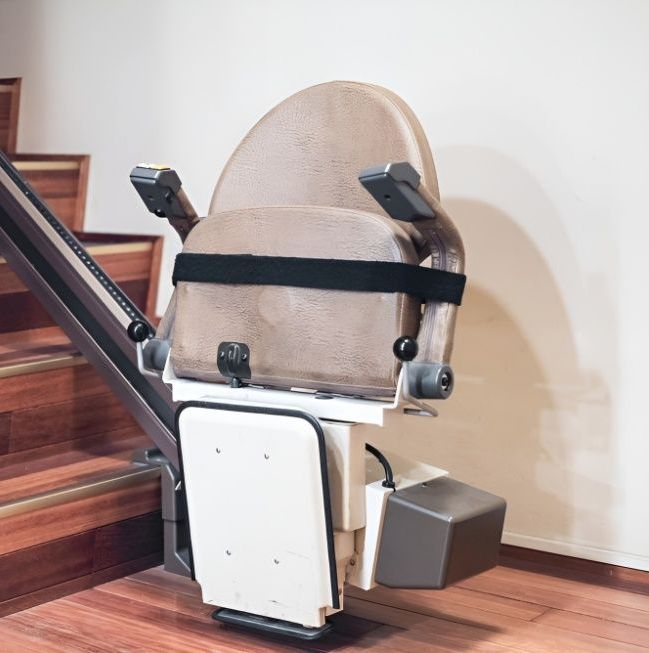 A Stair Lift is Sitting Next to a Set of Wooden Stairs — Mick's Carpentry & Maintenance In Machans Beach, QLD