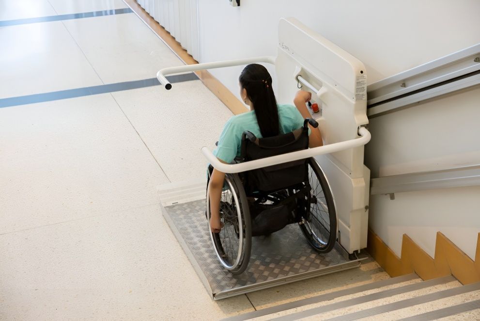 A Woman in a Wheelchair is Using a Lift to Get Up the Stairs — Mick's Carpentry & Maintenance In Machans Beach, QLD