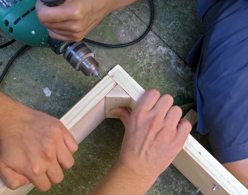 A Person is Using a Drill on a Piece of Wood — Mick's Carpentry & Maintenance In Machans Beach, QLD