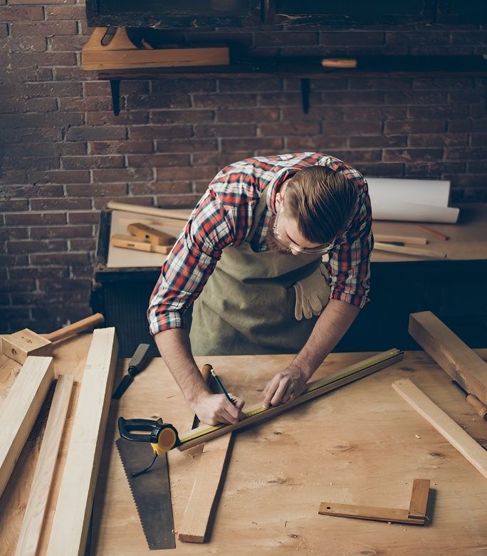 A Man is Measuring a Piece of Wood With a Tape Measure — Mick's Carpentry & Maintenance In Machans Beach, QLD