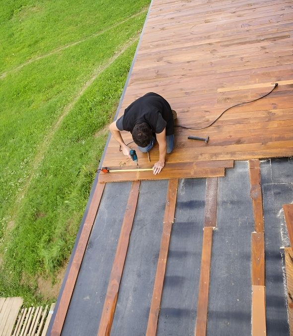 A Man is Drilling a Piece of Wood on a Roof — Mick's Carpentry & Maintenance In Machans Beach, QLD
