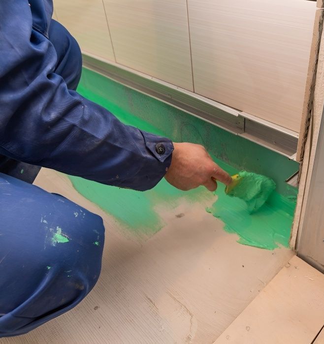 A Person is Kneeling Down and Painting the Floor With a Brush — Mick's Carpentry & Maintenance In Machans Beach, QLD