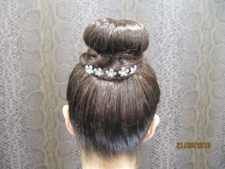 Una mujer lleva un moño con flores.