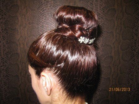 Una mujer lleva el pelo recogido en un moño con una pinza de diamantes de imitación.