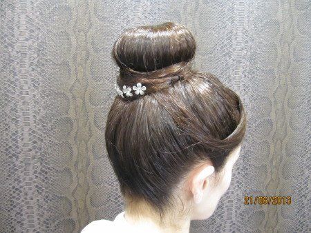 Una mujer lleva el pelo recogido en un moño con una horquilla.