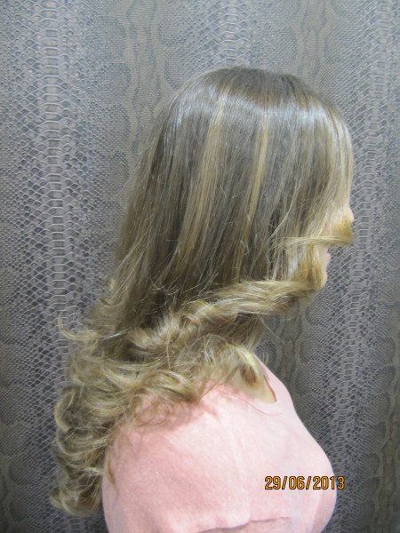 Una mujer con cabello largo y rubio lleva un suéter rosa.