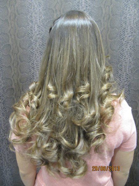 Una mujer con cabello largo y rizado lleva una camisa rosa.