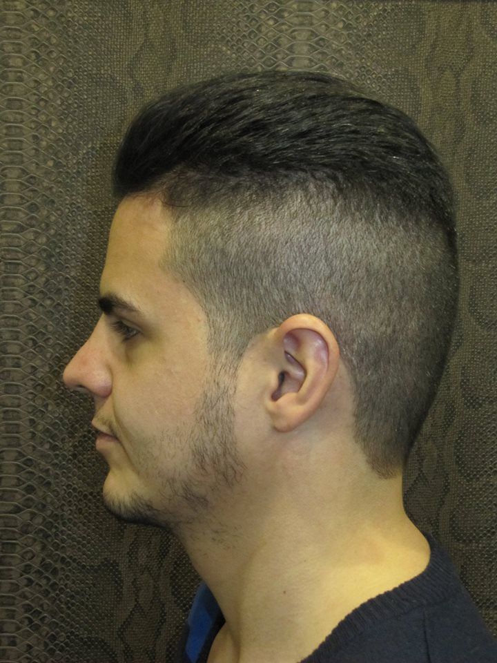 Un hombre con la cabeza rapada y barba lleva una camisa negra.