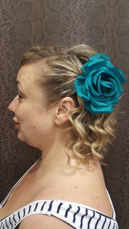 Una mujer lleva una rosa azul en el pelo.