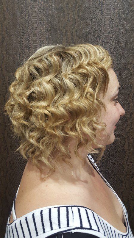 Una mujer con cabello rubio y rizado lleva una camisa a rayas.