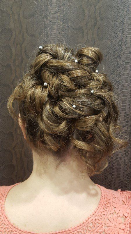 La parte posterior de la cabeza de una mujer con un moño y perlas en el pelo.