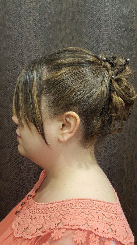 Una mujer lleva una blusa rosa y tiene el cabello recogido en un moño.