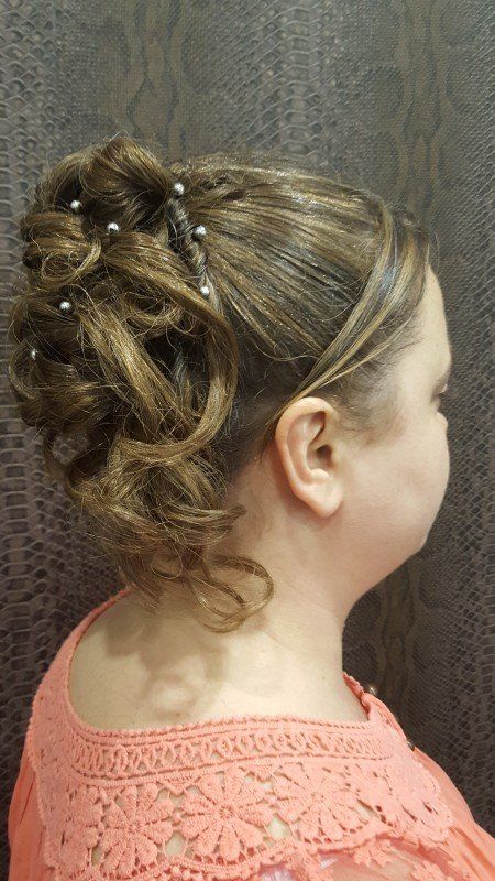 Una niña lleva un moño con perlas en el pelo.