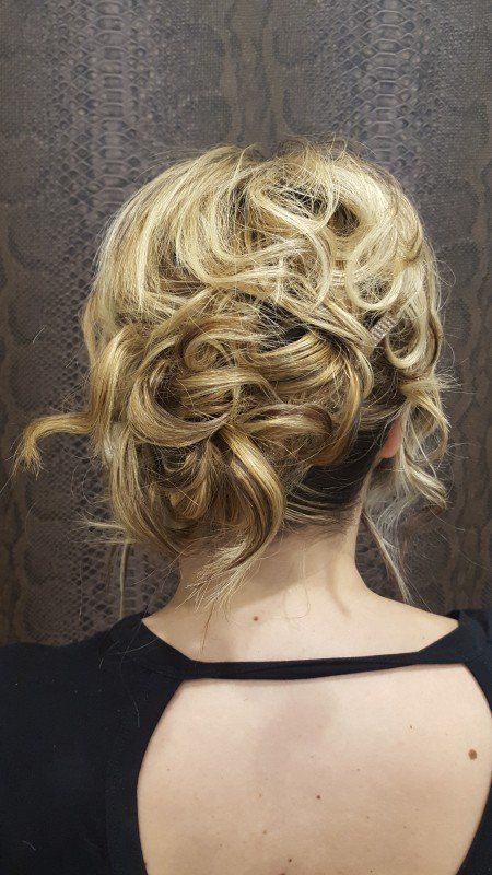 La espalda de una mujer con cabello rubio recogido en un moño desordenado.