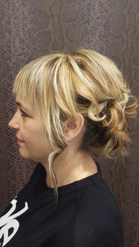 Una mujer con cabello rubio recogido en un moño lleva una camisa negra.