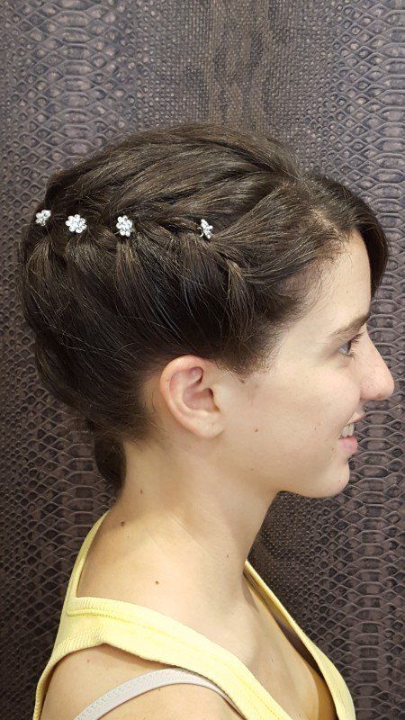 Una mujer lleva una camiseta amarilla y tiene una trenza en el pelo.