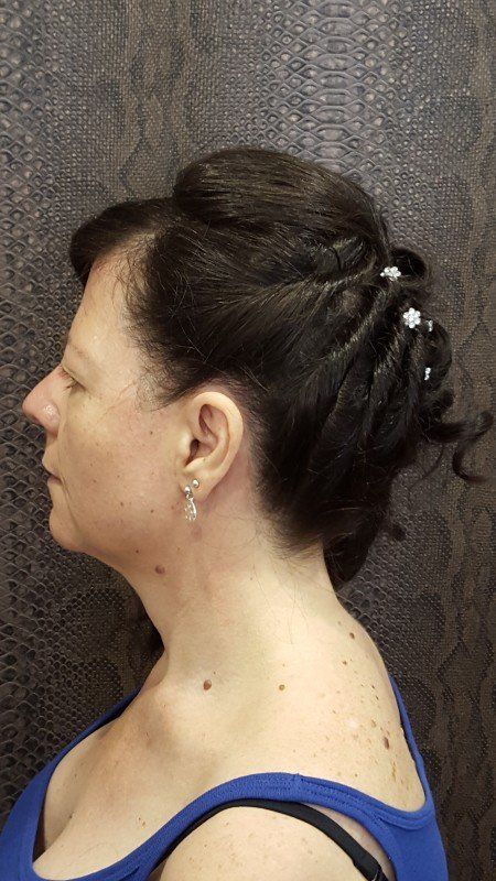 Una mujer lleva una camiseta azul sin mangas y tiene el pelo recogido en un moño.