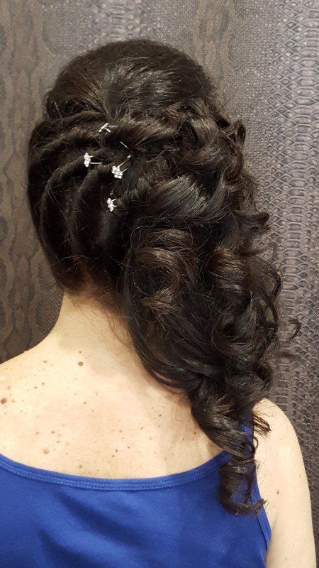 La parte de atrás de una mujer que viste una camiseta azul sin mangas y tiene el cabello recogido mitad arriba y mitad abajo.