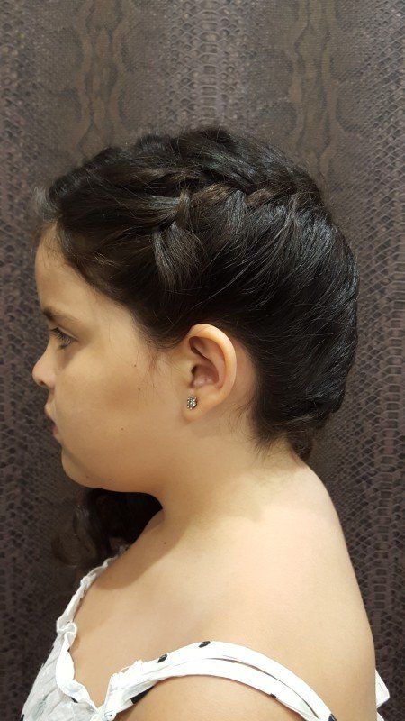 Una niña lleva un peinado trenzado y pendientes.