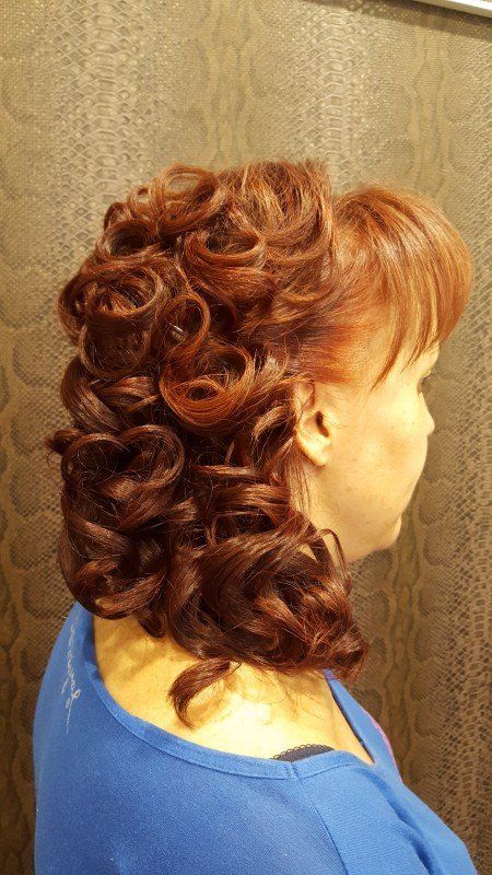 Una mujer con cabello rojo y rizado lleva una camisa azul.