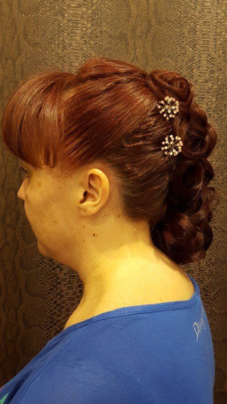 Una mujer con cabello rojo lleva una camisa azul y tiene el cabello recogido en un moño.