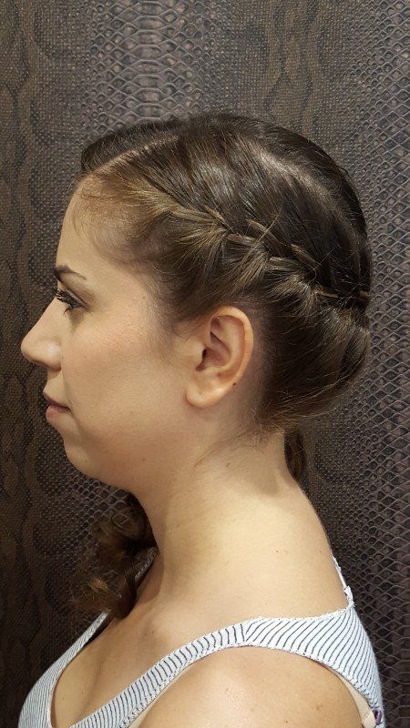 Una mujer lleva un moño trenzado y una camiseta sin mangas de rayas.