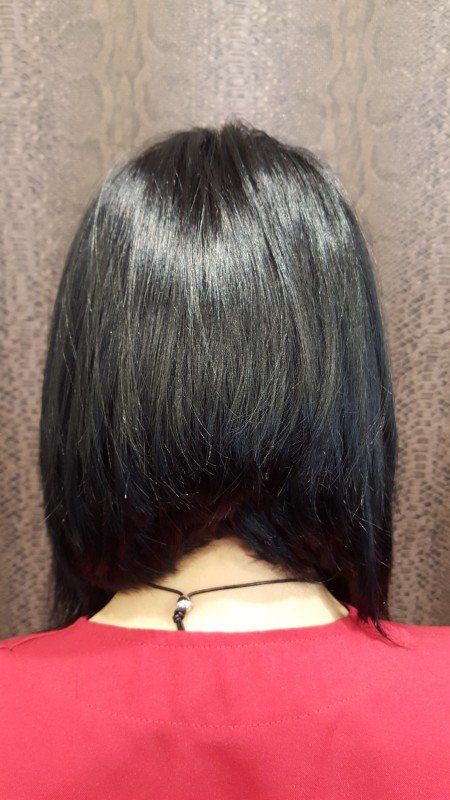 La parte posterior de la cabeza de una mujer con cabello negro y una camisa roja.