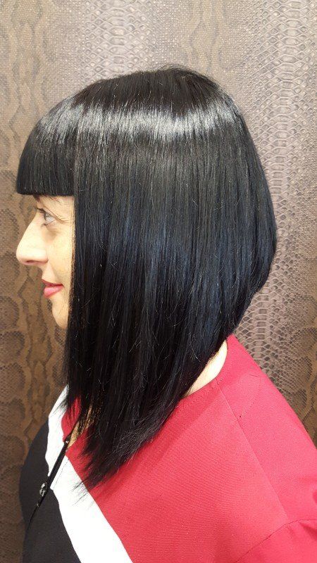 Una mujer con cabello largo y negro lleva un suéter rojo.