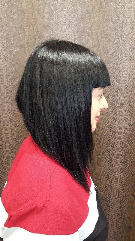 Una mujer con cabello largo y negro lleva un suéter rojo y blanco.