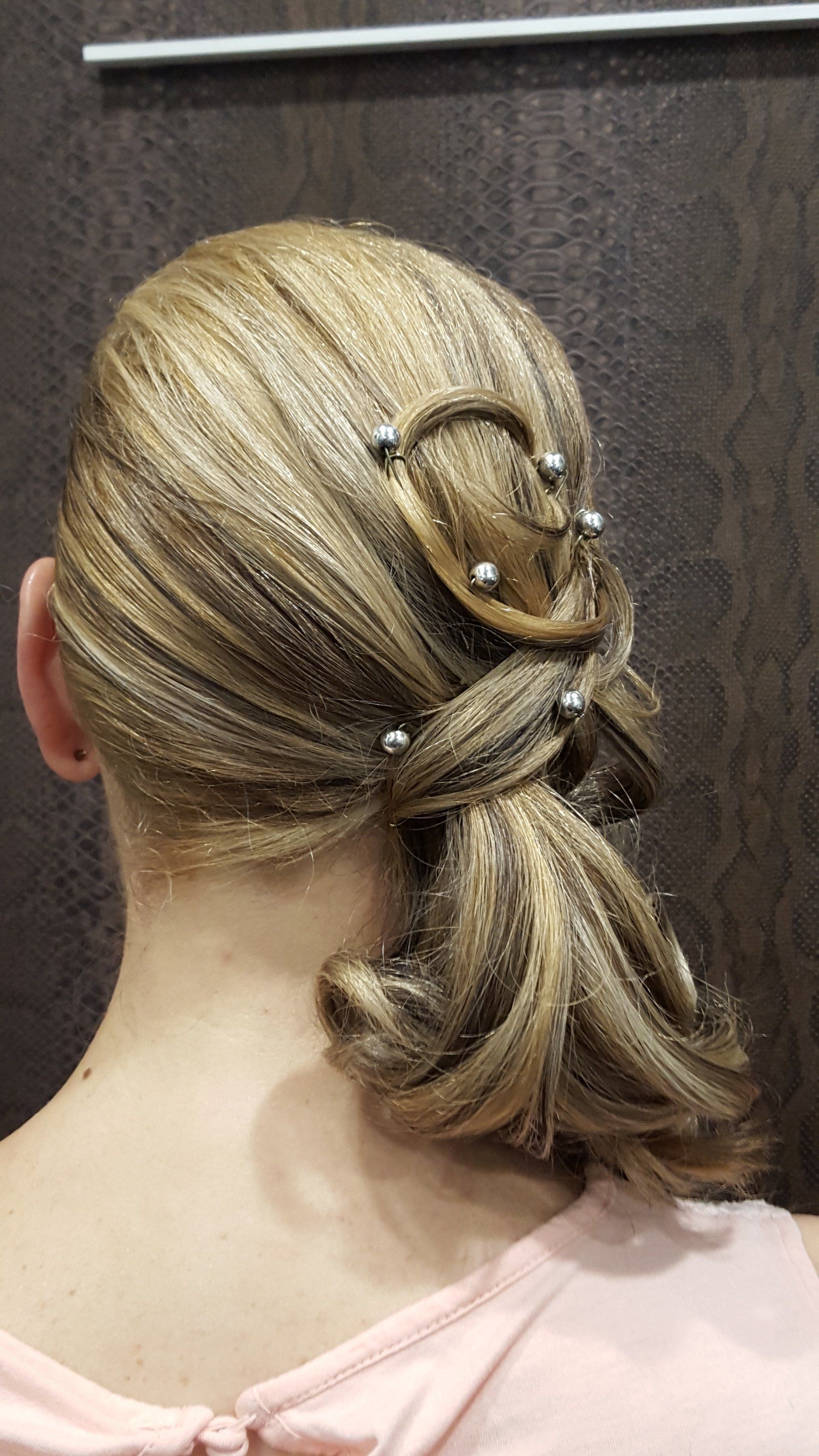 Una mujer lleva el pelo recogido en un moño con perlas.