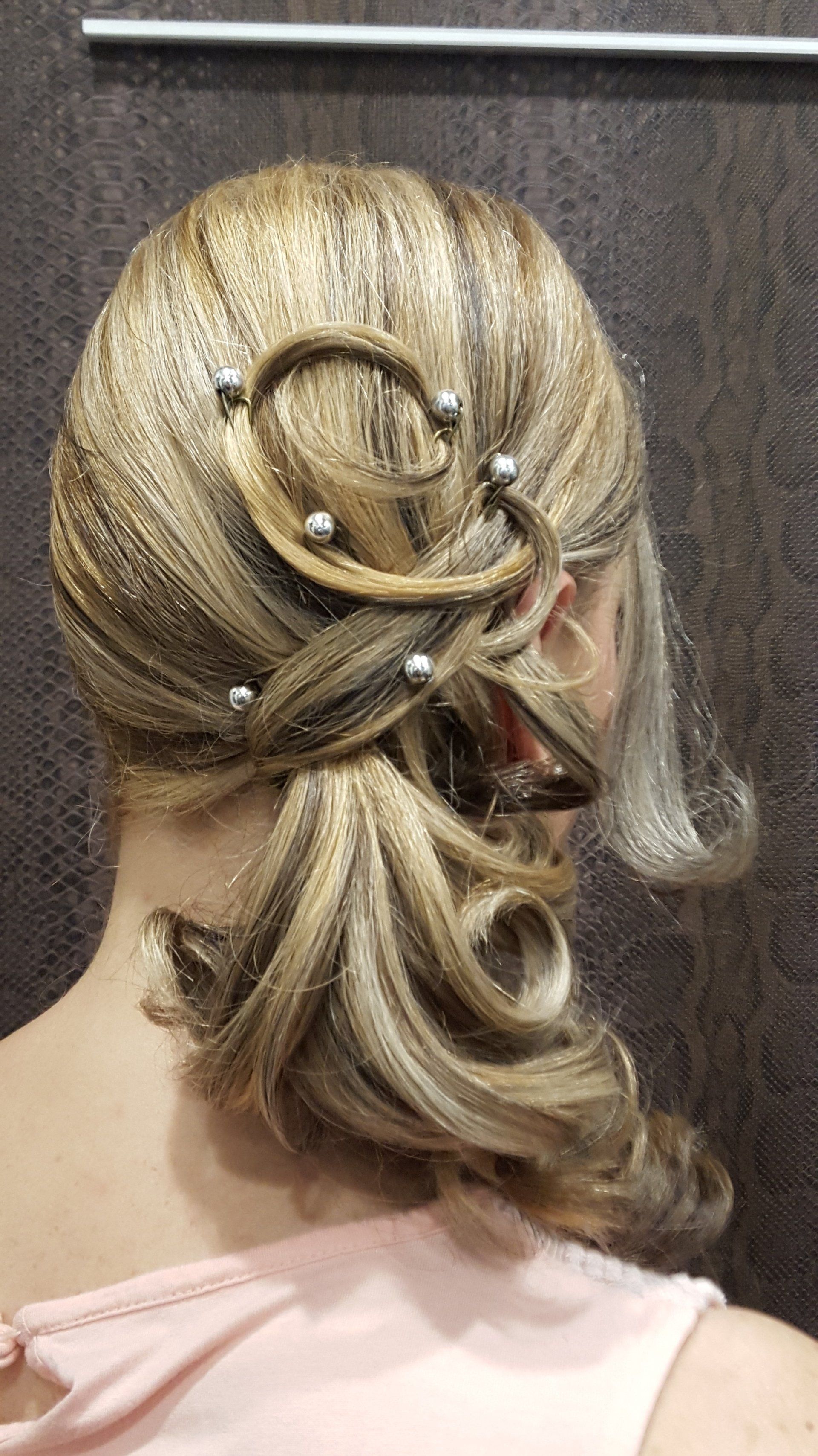 La parte posterior de la cabeza de una mujer con una cola de caballo y perlas en el cabello.