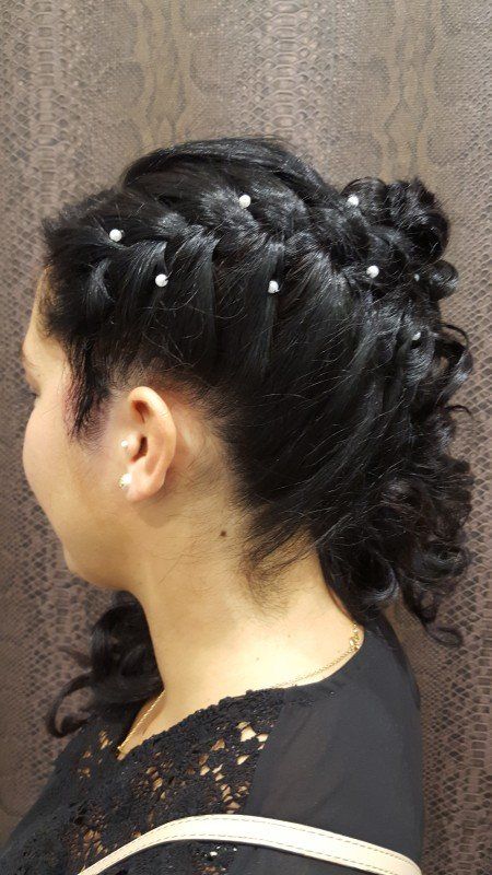 Una mujer lleva un moño trenzado con perlas en el pelo.