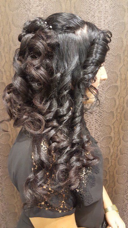 Una mujer con cabello largo y rizado lleva un peinado trenzado.