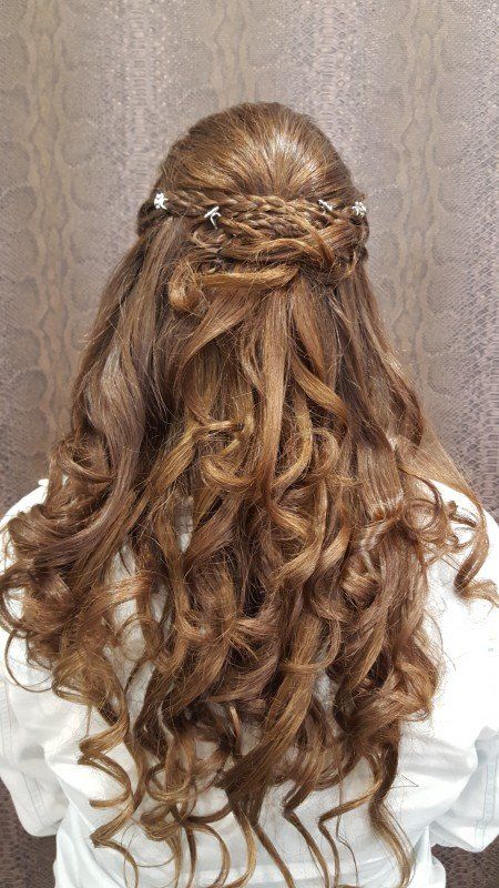 Una mujer con cabello largo y rizado lleva un peinado mitad recogido mitad suelto.