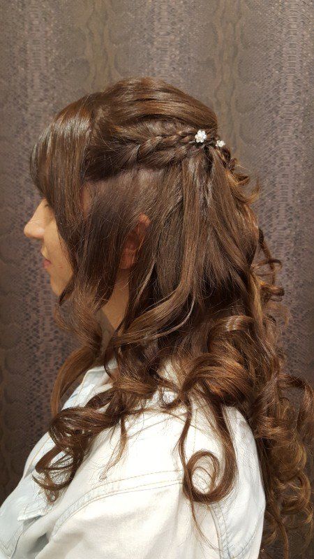 Una mujer con cabello largo y castaño lleva un peinado mitad recogido y mitad suelto.