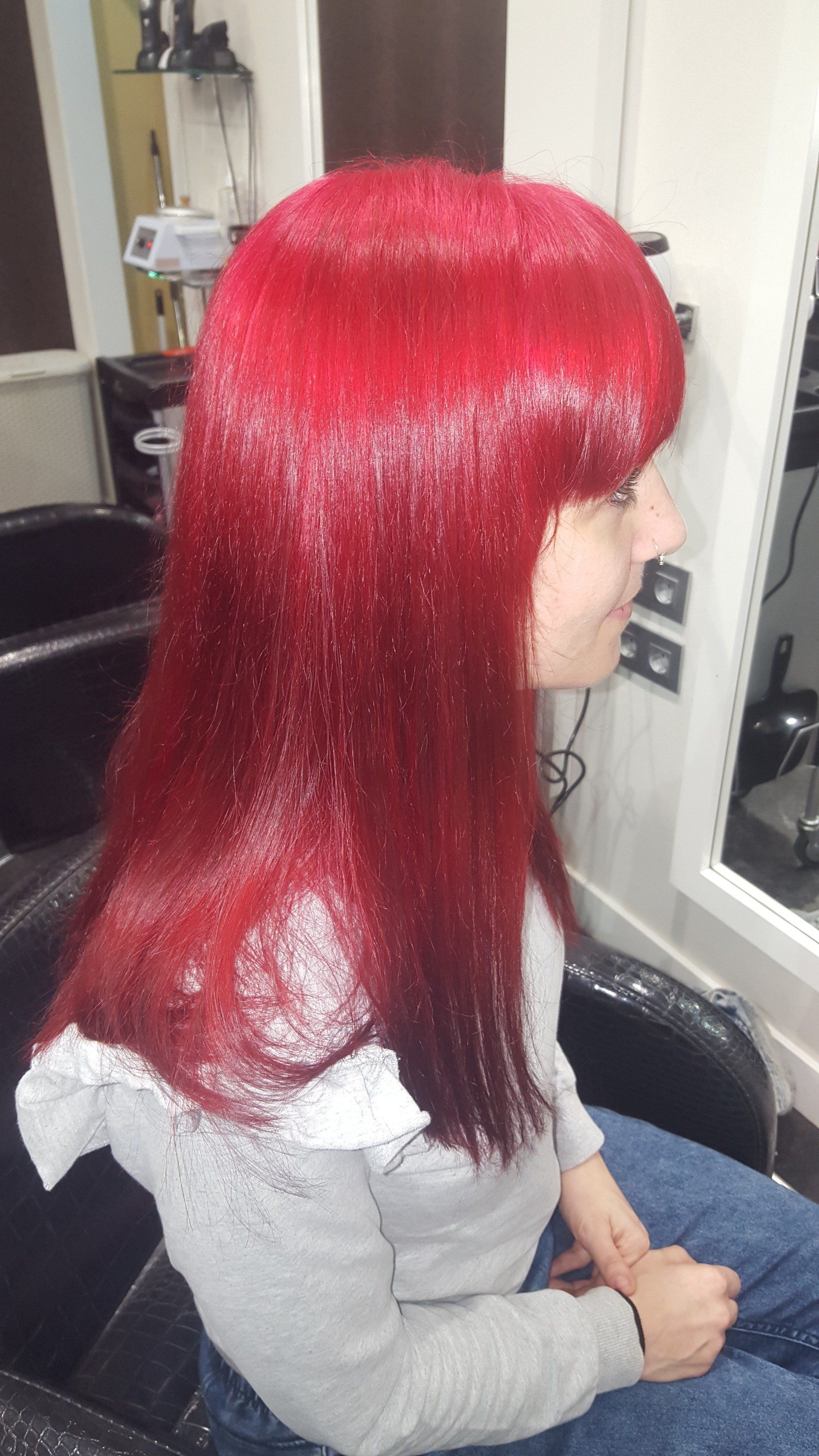 Una mujer con cabello rojo está sentada en una silla en un salón.