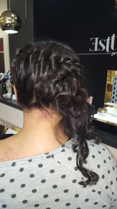 Una mujer lleva una camisa de lunares y tiene el cabello recogido en una trenza.