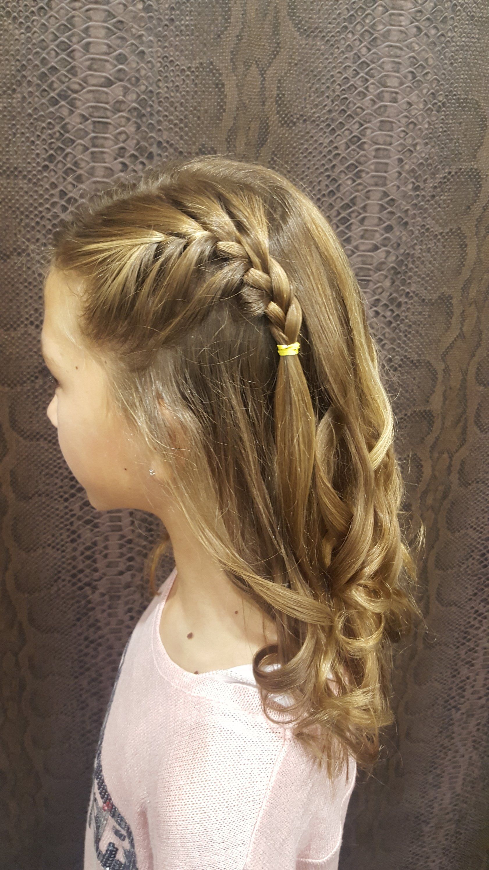 Una niña con cabello largo lleva un peinado trenzado.