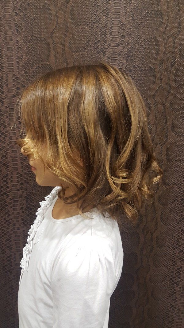 Una niña con cabello corto y castaño lleva una camisa blanca.